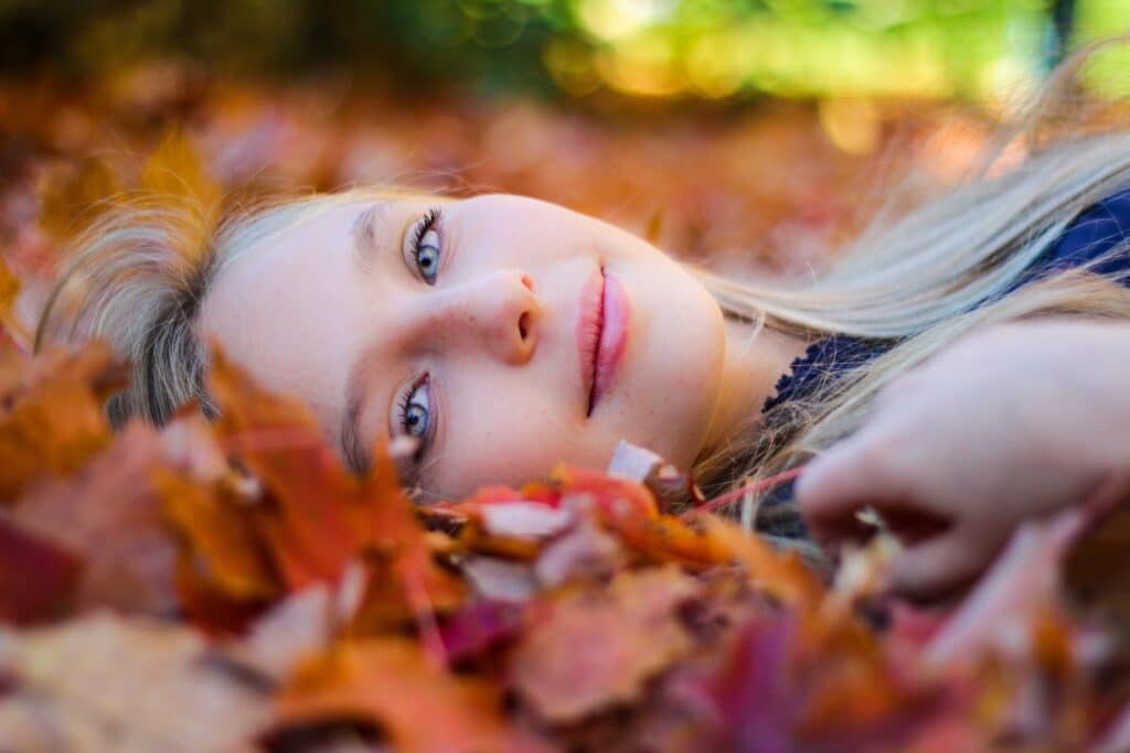 A capture of a girl lying in the maple leaves posing for the camera