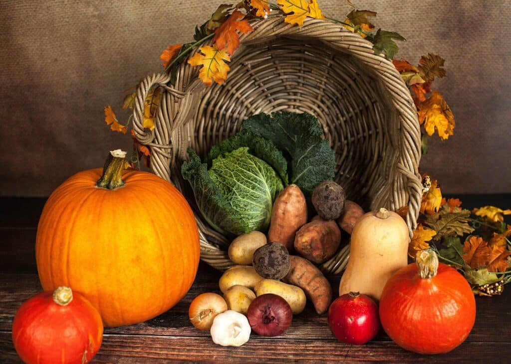 A capture of all harvest with pumpkins and other vegetables out of the fall leaves decorated basket