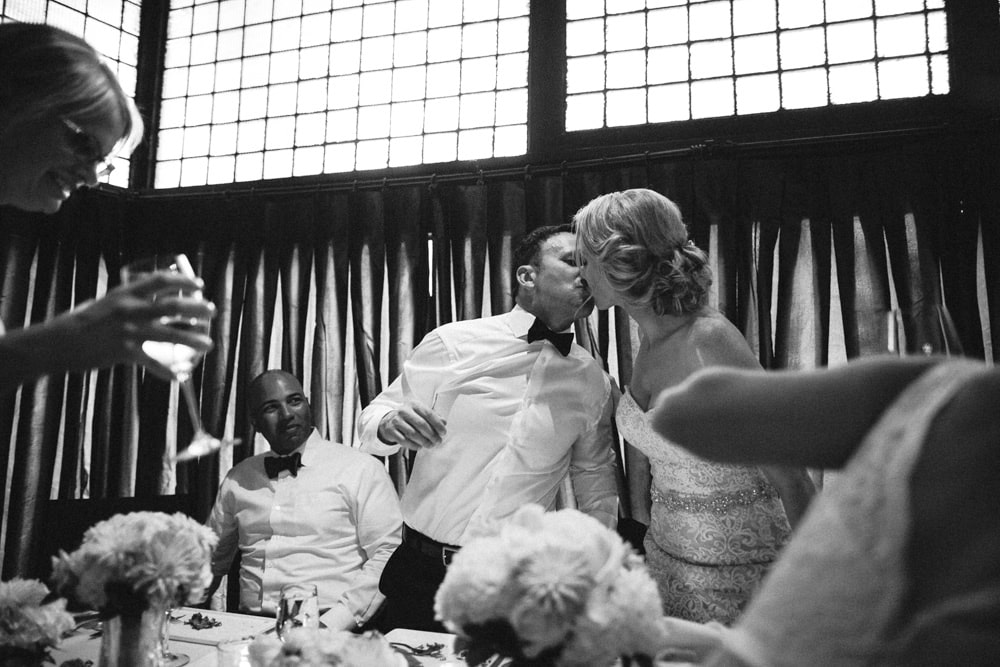 candid picture of bride and groom kissing in front of guests