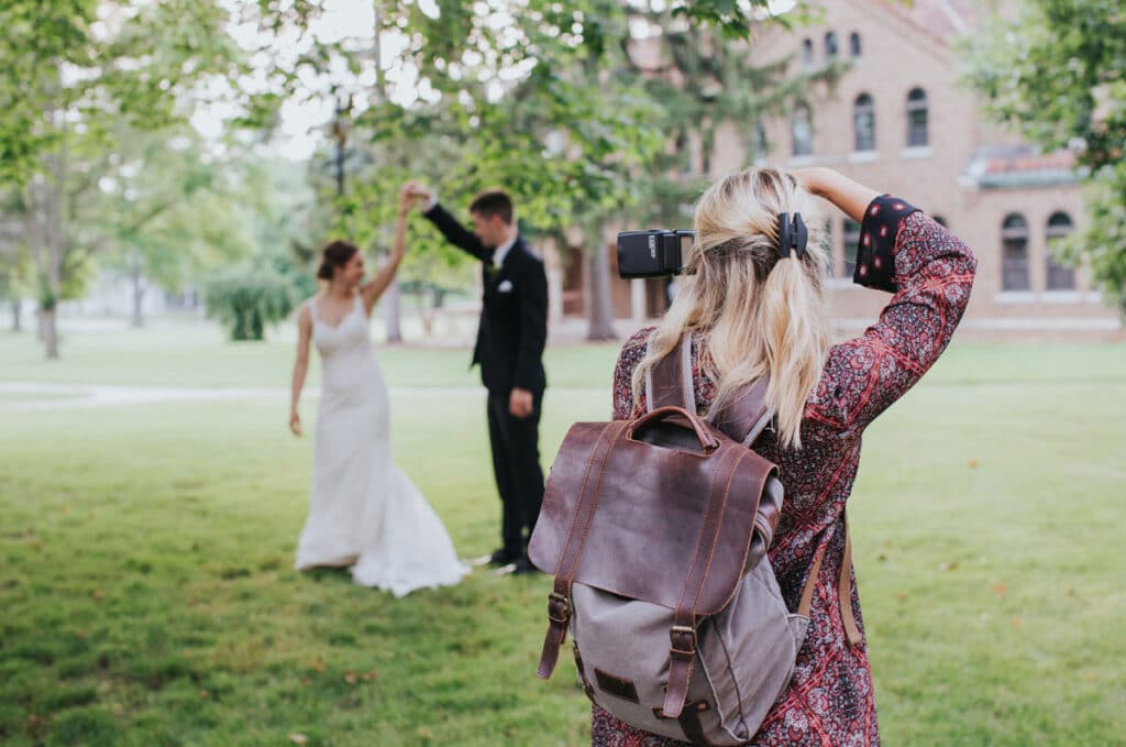 female photographer taking pictures of a couple twirling in the garden