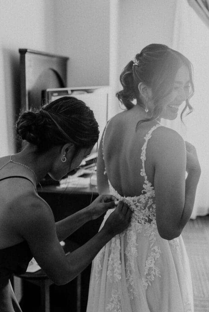 pre ceremony capture of a bridesmaid fixing brides dress