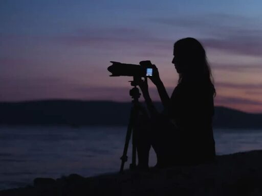 A dim view of girl adjusting the camera on a tripod