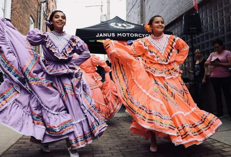 girls holding their dresses and dancing on street