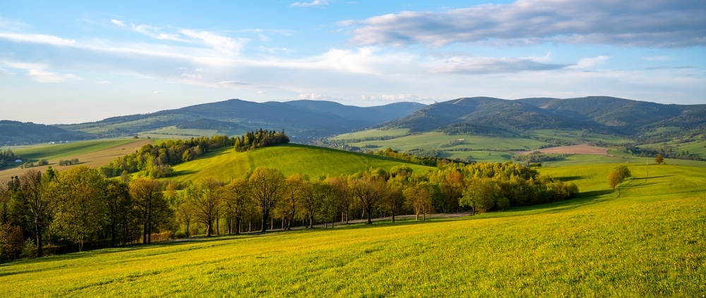 A Scenic View Of Rolling Green Hills And Distant Mountains