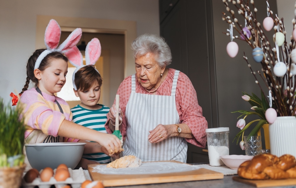 Grandmother With Grandchildren Preparing Traditional Easter Meals Kneading Dough For easter cross buns.