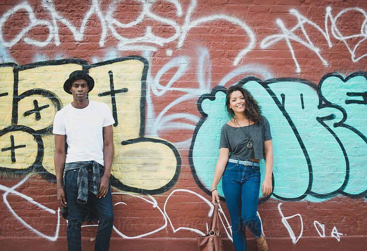 a couple happily posing for valentines photoshoot standing in front of a grafitti wall