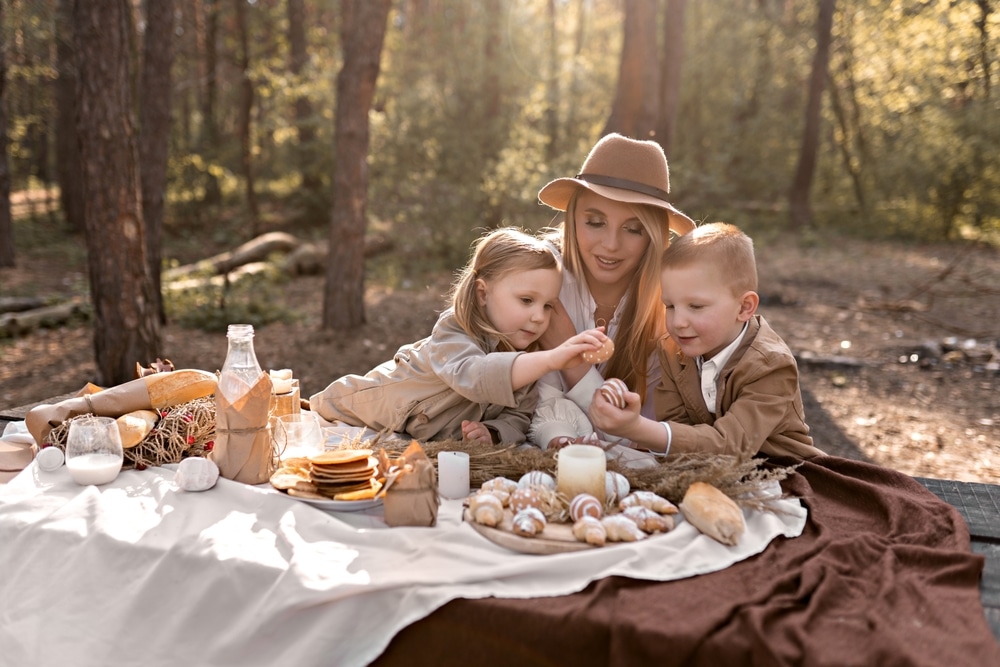 Family With Children Is Enjoying Easter Picnic In Spring Garden