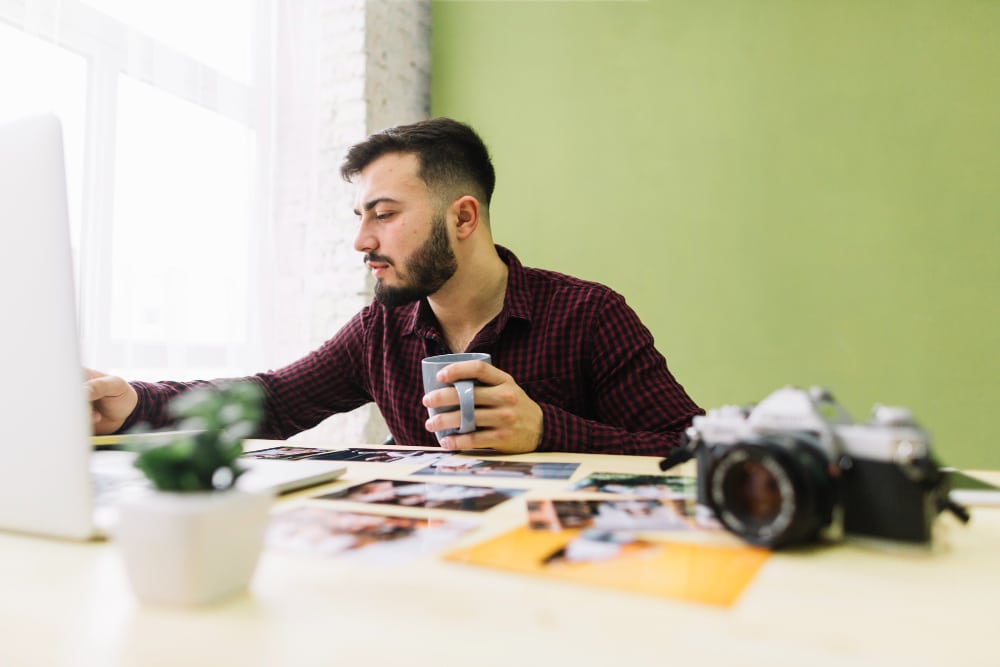 an employee working, holding a cup, blurred view of a camera placed on table
