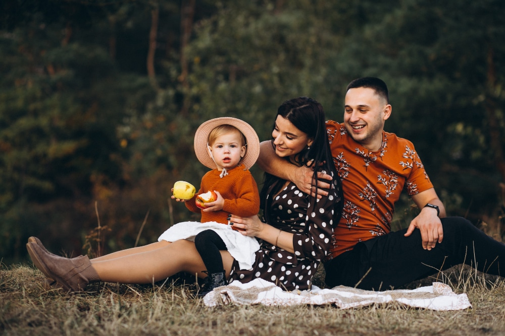 Family with their little daughter having picnic in a field
