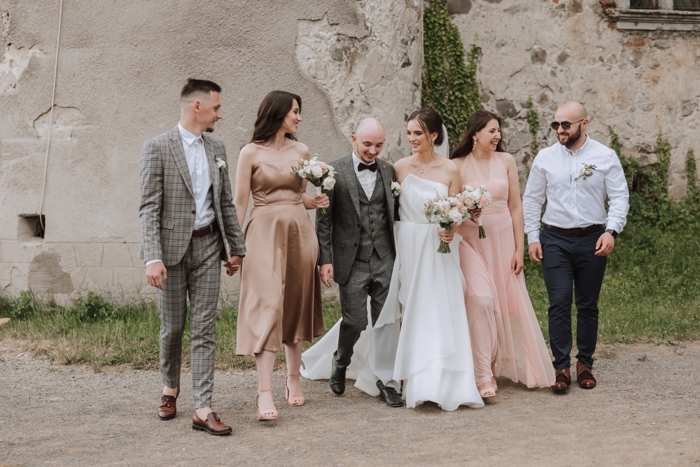 The bride and groom with their friends pose on the old wall. 