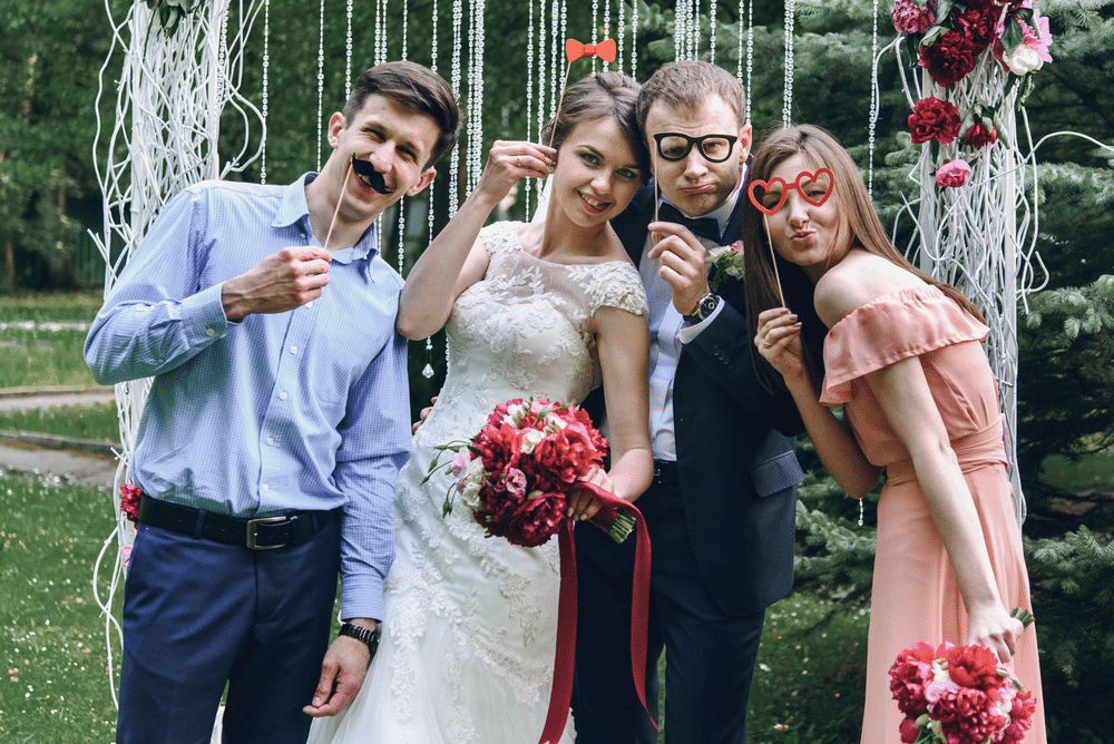 elegant stylish happy guests and bride and groom having funny photos on the background of arch photo booth