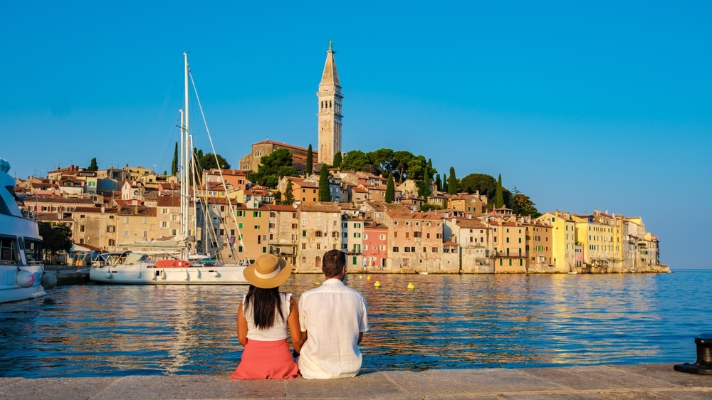 A Couple Sits Side By Side On The Waterfront 