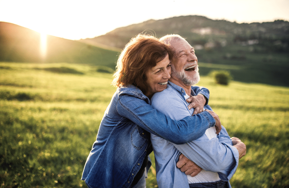 Side view of senior couple hugging outside in spring nature at sunset