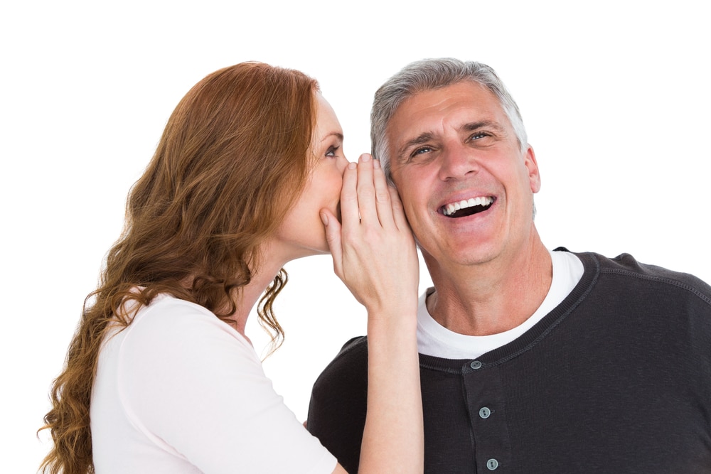 Woman Telling Secret To Her Partner On White Background